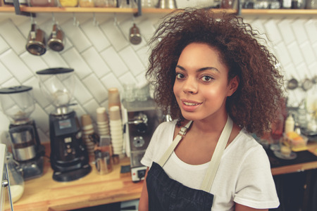 Cheerful woman near appliances and glassware in cafeの写真素材