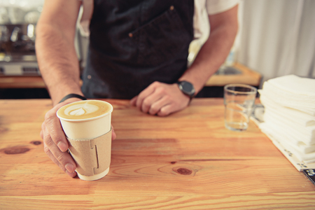 Bartender giving tasty coffee to visitor in cafeの写真素材