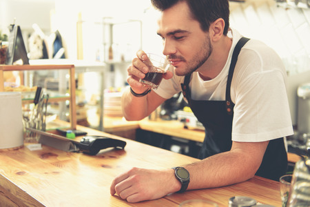 Outgoing counterman trying glass of appetizing teaの写真素材