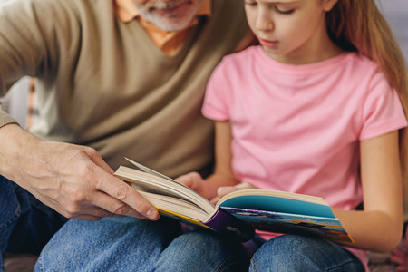 Pretty child reading story with grandparentの写真素材