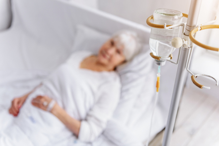 Serene pensioner is on drip bulb in apartmentの写真素材