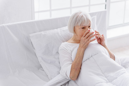 Grandmother tasting mug of delicious beverageの写真素材