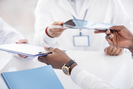 Doctor giving clipboard to his colleaguesの写真素材