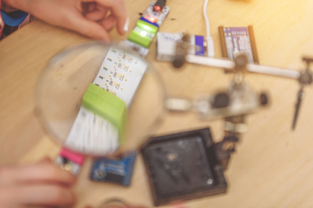 Young technician is using loupe for investigating small spare parts. Close up of handsの写真素材