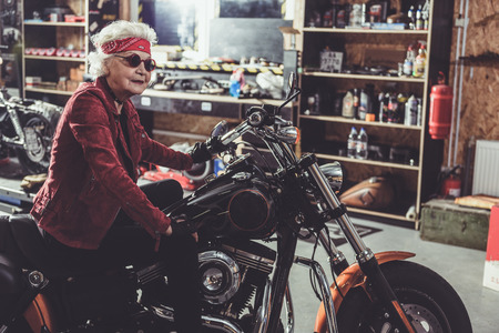 Cheerful pensioner locating on bike in garageの写真素材