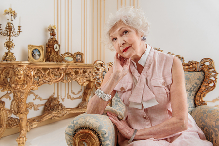 Elegant senior woman sitting on luxury armchairの写真素材