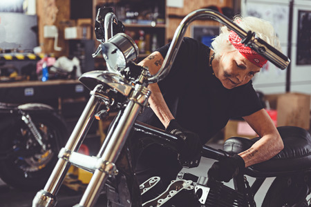 Serene granny reconditioning motorcycle in garage