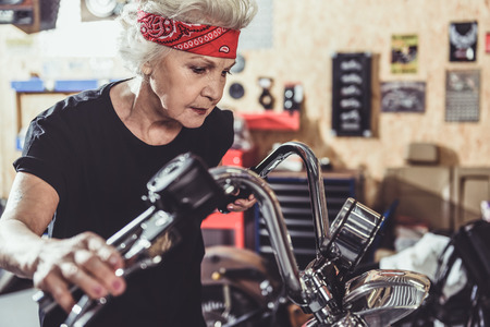 Serene female retiree situating near motorcycleの写真素材