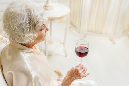 Old lady drinking wine at homeの写真素材