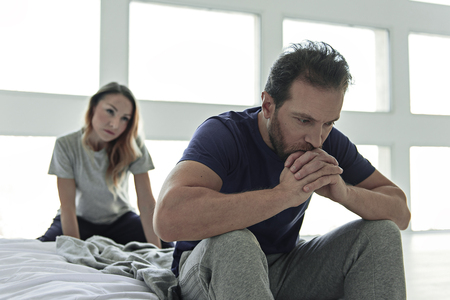 Depressed man sitting in bedroomの写真素材