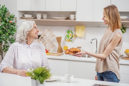 Cute daughter treating her mom with breakfastの写真素材
