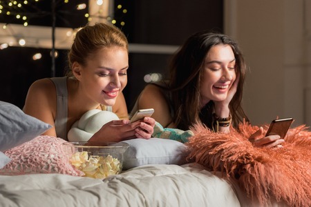 Smiling female friends looking at mobileの写真素材