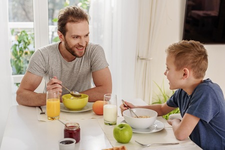 Happy man enjoying healthy breakfast with his childの写真素材