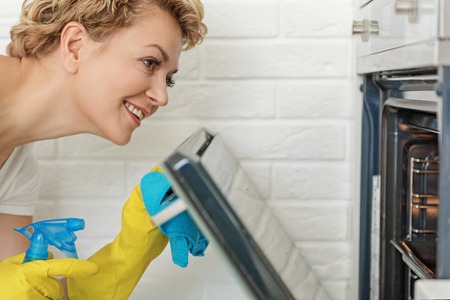 Active smiling woman cleaning kitchenの写真素材