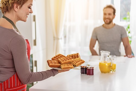 Happy married couple having breakfast in kitchenの写真素材