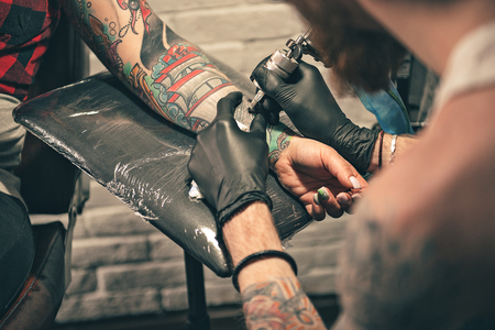 Male in gloves doing tattoo on handの写真素材