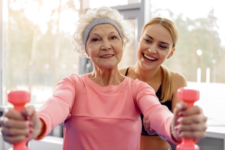 Cheerful grandmother making exercises in gymの写真素材