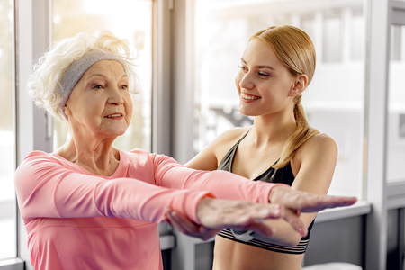 Beaming retiree making workout in fitness centerの写真素材
