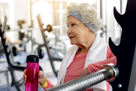 Happy grandmother tasting beverage in fitness centerの写真素材
