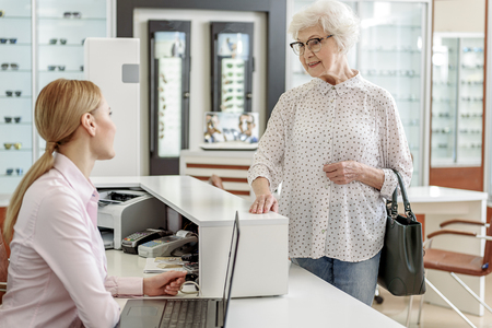 mature woman talking with shop assistantの写真素材
