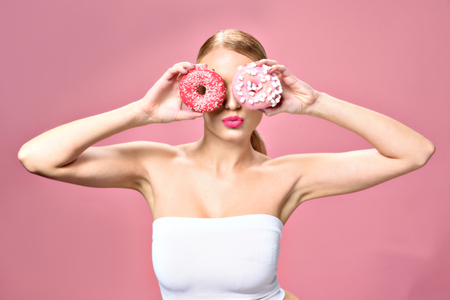 Young woman keeping two doughnutsの写真素材