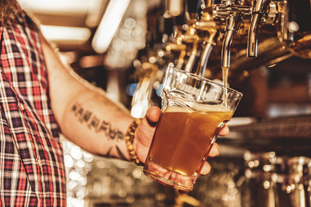Male arm filling cup of beerの写真素材