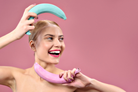 Smiling attractive girl holding color bananasの写真素材