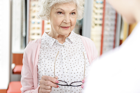Smiling mature woman keeping eyewearの写真素材