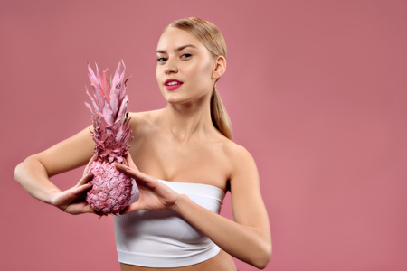 Attractive girl with ananas posing at cameraの写真素材