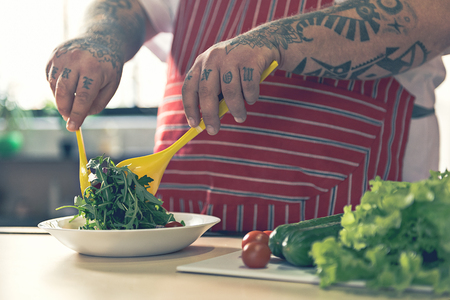 Fat man cooking fresh saladの写真素材