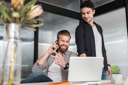Merry smiling male colleagues working