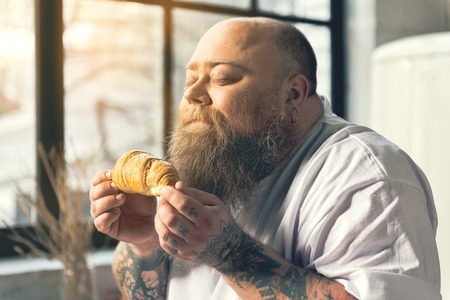 Hungry thick man smelling croissantの写真素材