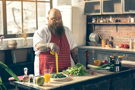 Thick guy cooking healthy food with lazinessの写真素材