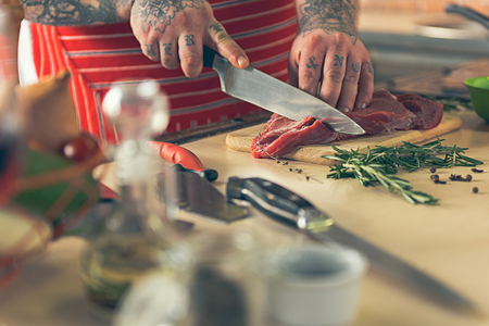Male chef hands cutting meat on boardの写真素材