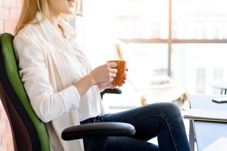 Cheerful girl taking pause for hot beverageの写真素材