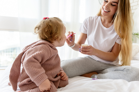 Joyful parent giving spoon with porridge to babyの写真素材