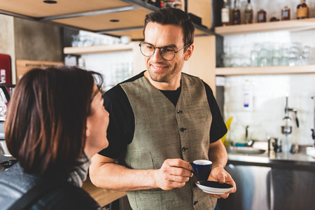 Cheerful barista putting cup of coffeeの写真素材