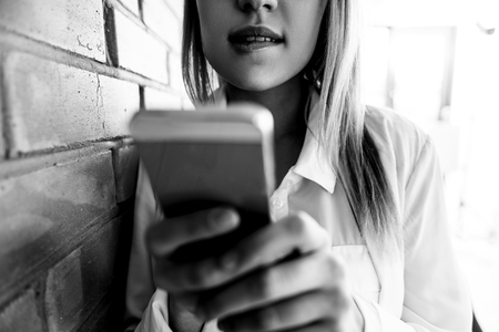 Mysterious girl leaning against brick wallの写真素材