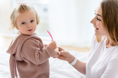 Happy mother feeding toddler with breakfastの写真素材