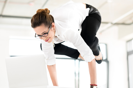 Happy secretary doing yoga at workの写真素材