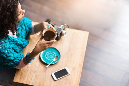 Pensive young woman drinking cup of hot coffeeの写真素材