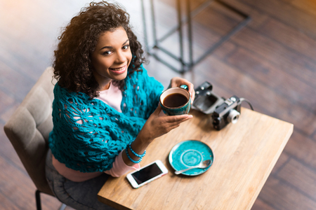 Charming mulatto girl drinking hot beverageの写真素材