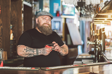 Fat bartender wearing cap laboring in pubの写真素材