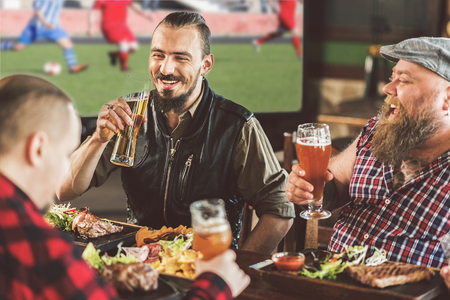 Bearded guys relaxing with beer in sports barの写真素材
