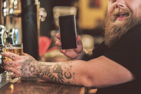Joyful fat man showing his handset with smileの写真素材