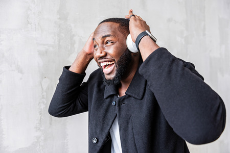 Happy young african guy listening to music via smart phoneの写真素材