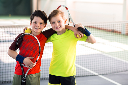 Happy children entertaining on tennis courtの写真素材