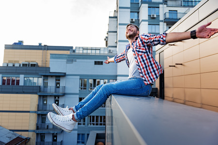 Joyful guy relaxing on rooftop terraceの写真素材