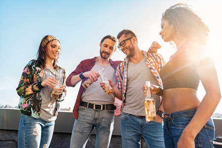 Joyful friends drinking alcohol on rooftop terraceの写真素材