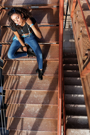 Relaxed mulatto girl sitting on stepsの写真素材